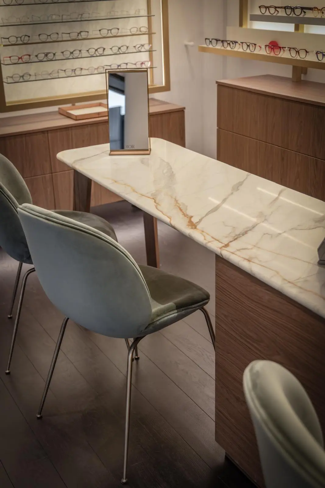 Table de conseil en marbre et fauteuils de velours, devant les présentoirs de montures